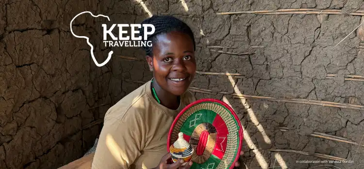 A woman holding handmade woven crafts sits in a simple clay-walled room, smiling, with travel‑themed branding displayed in the top corner