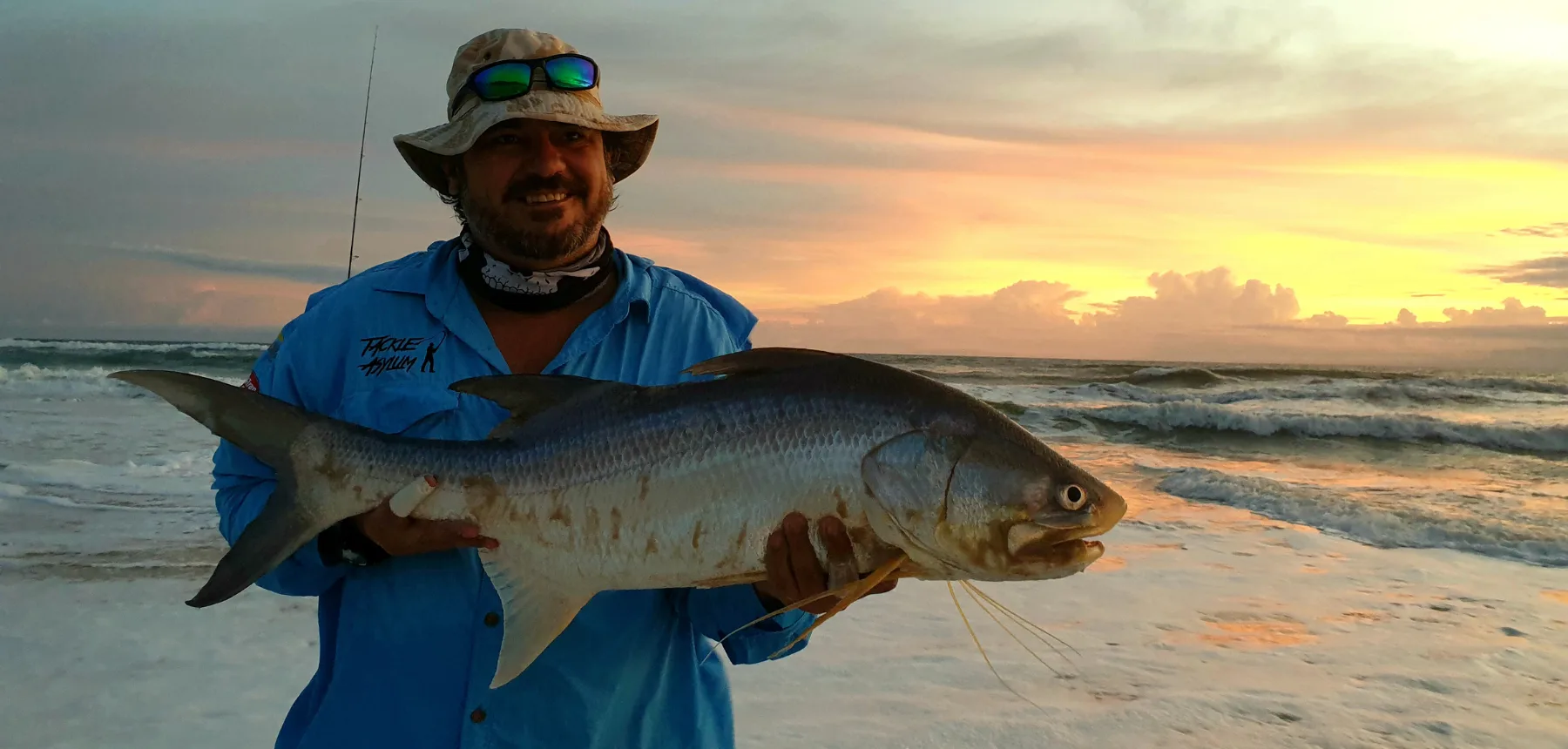 Man holding fish on beach at sunrise