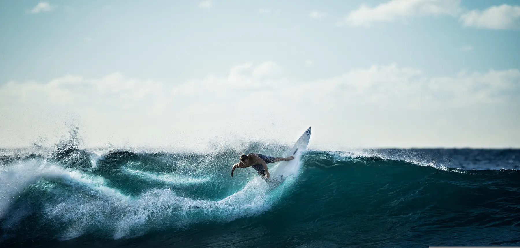 Surfer riding powerful ocean wave with spray and motion in open water