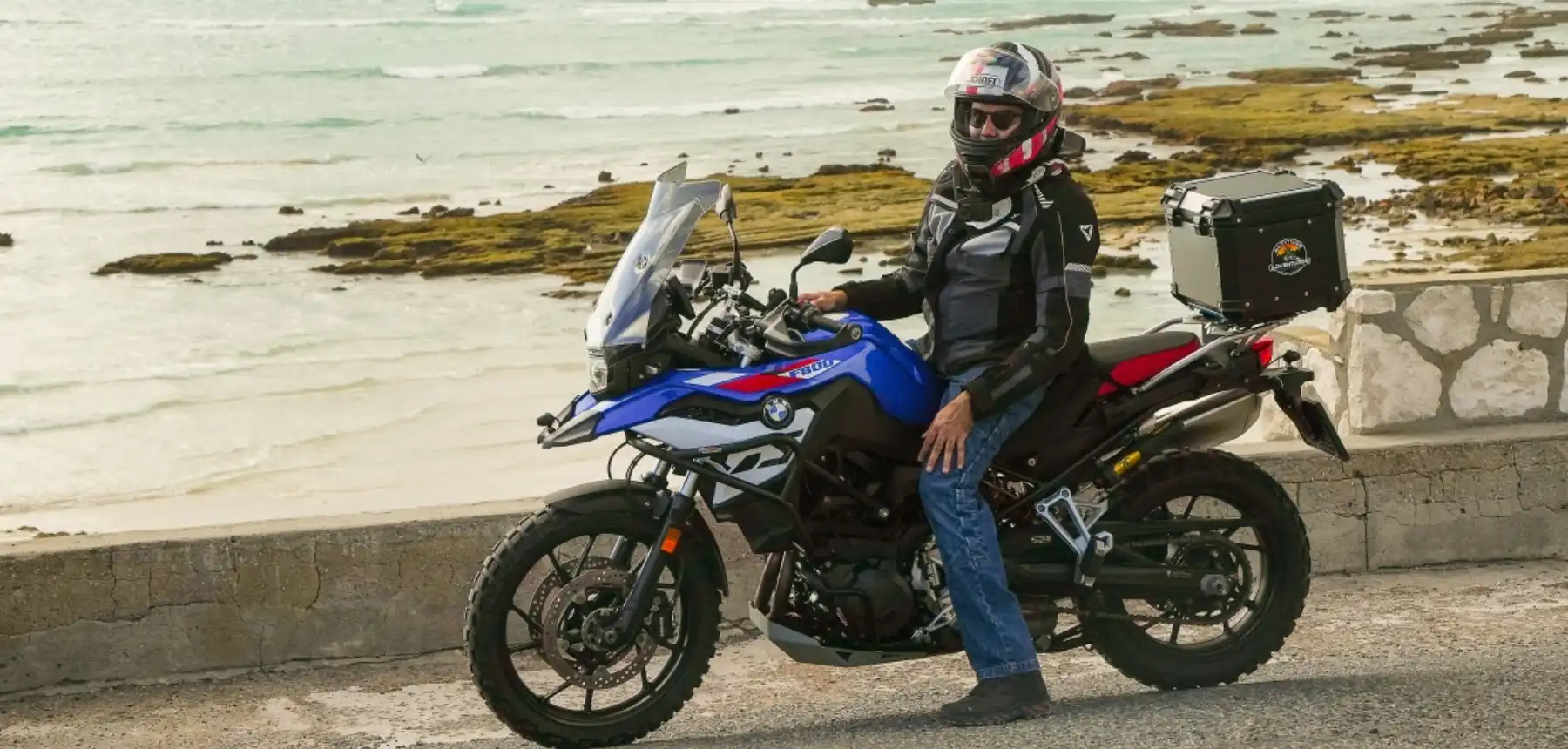 Traveller on a motorcycle beside a coastal road during an African travel adventure