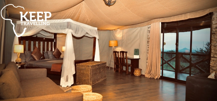 Spacious safari lodge room with a mosquito-netted bed, seating area and private balcony