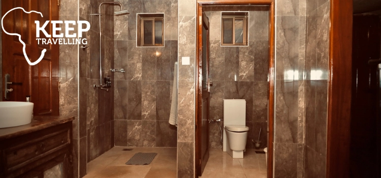 Modern private bathroom with a walk-in shower, washbasin and separate toilet at Serengeti Safari Lodge